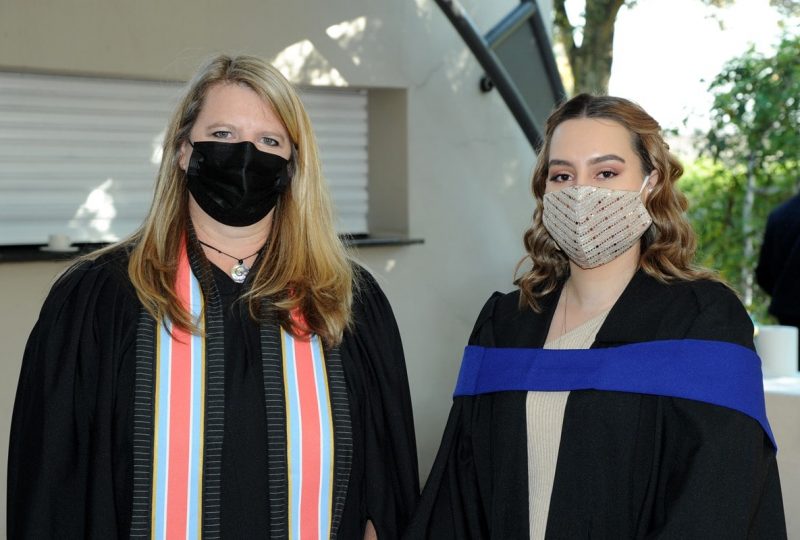 Two newly graduated AAA School of Advertising students wearing their graduation robes
